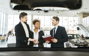 Ein Paar wird in einem Autohaus von einem Verkäufer beraten.